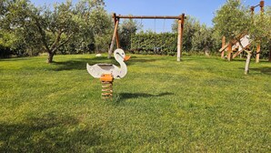 Un parque infantil con un conjunto de columpios de madera y un columpio con forma de cisne.