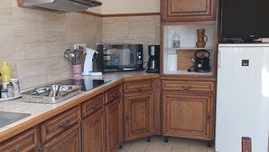Eine Küche mit Holzschränken, einer Mikrowelle, einer Kaffeemaschine und einem Kühlschrank.