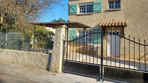 Ein Steinhaus mit einem Metallgitter, grünen Fensterläden und einem Ziegeldach.