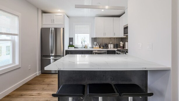 Una cocina moderna con una isla grande, electrodomésticos de acero inoxidable y un diseño minimalista.