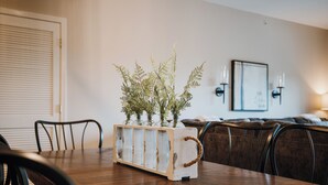 Una mesa de comedor con una mesita auxiliar de madera rústica que sostiene un arreglo floral.