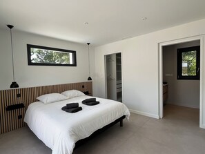 A modern bedroom with a bed, a wardrobe, and a window. - Villas-des-oyats Seignosse Villa Ophila Climatisée - Piscine Chauffée (Seignosse)