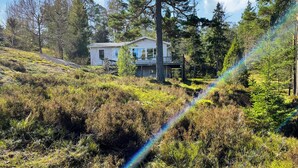 Et hus med balkon, omgivet af tæt skov og vegetation.