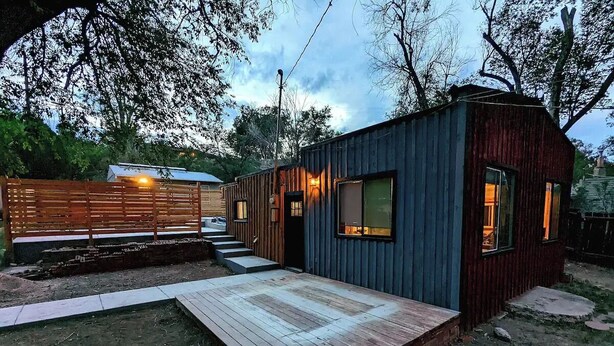 A small, rustic cabin with a wooden deck and a single window.