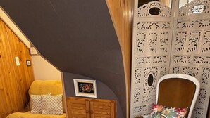 Een knus ingerichte kamer met een bank, een stoel, een kleine tafel en een kast.