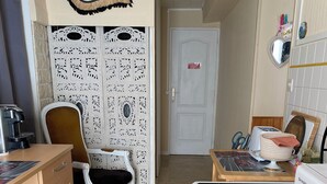 Een kleine keuken met een koffiezetapparaat, een broodrooster en een magnetron. Er staat een witte stoel en een decoratief paneel aan de muur.