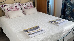 Een opgemaakt bed met een witte dekbedovertrek en twee gevouwen handdoeken.