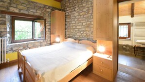 A bedroom with a stone wall, wooden bed, and a window with curtains. - Awesome home in Loazzolo with WiFi (Loazzolo)