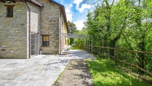 A stone building with a paved patio and a covered outdoor seating area. - Awesome home in Loazzolo with WiFi (Loazzolo)