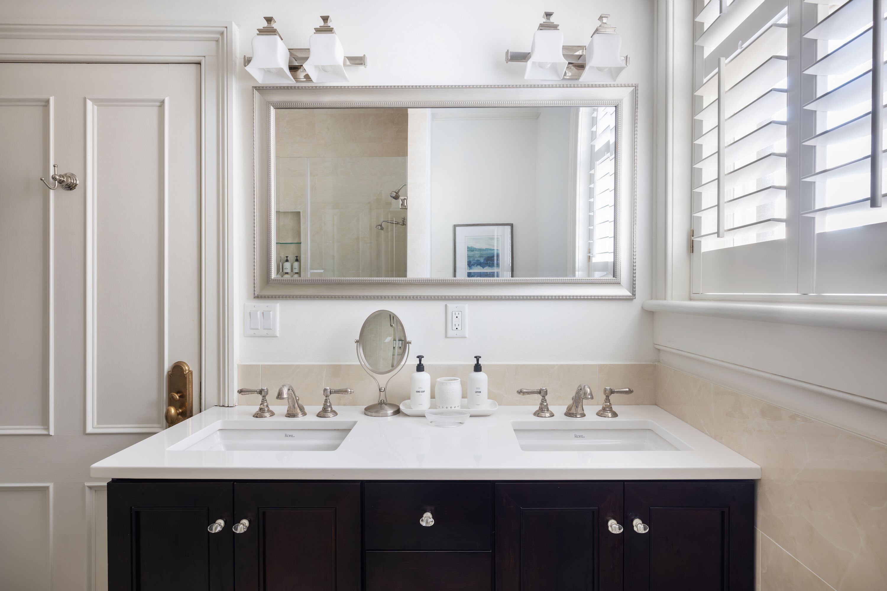 Une salle de bain avec deux lavabos, un grand miroir et des meubles de couleur sombre.