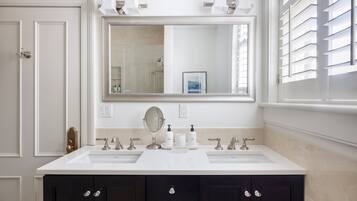 Une salle de bain avec deux lavabos, un grand miroir et des meubles de couleur sombre.