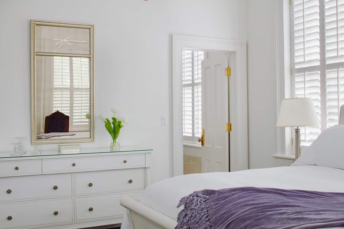Quarto com cama, penteadeira, espelho e porta.
