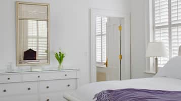 A bedroom with a bed, a dresser, a mirror, and a door.