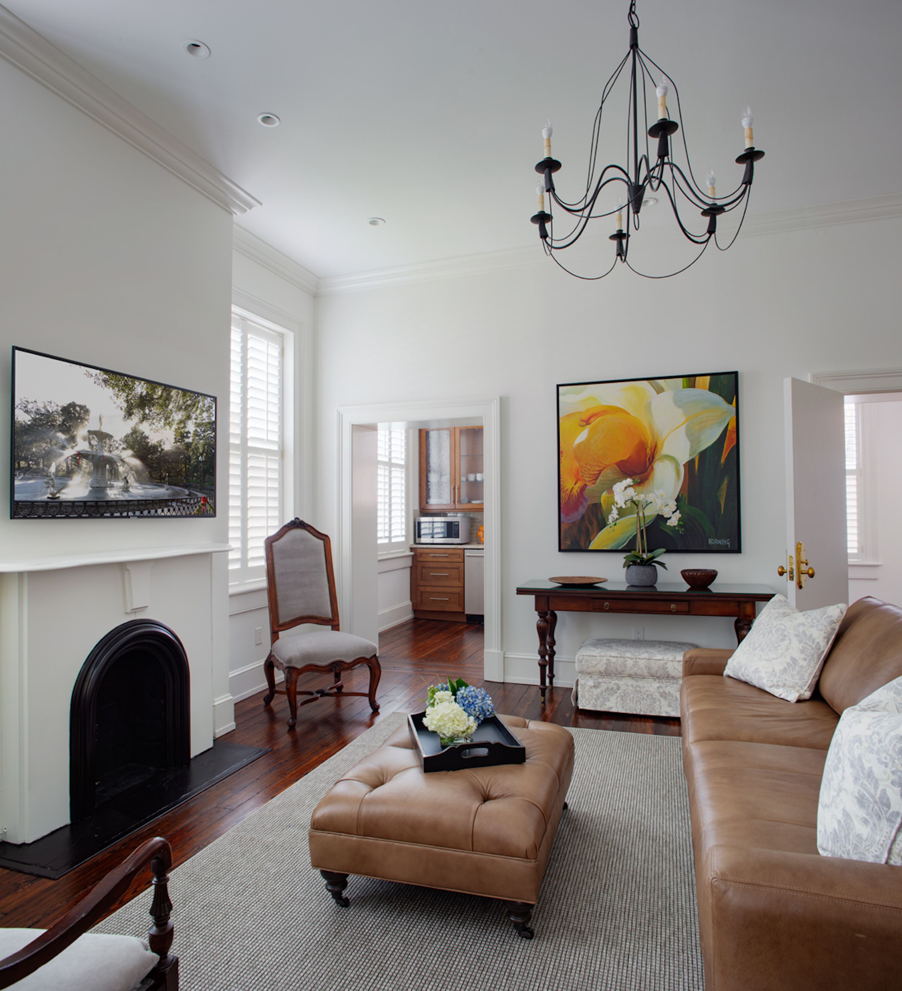 A spacious living room with a fireplace, a chandelier, a large painting, and a cozy seating area.