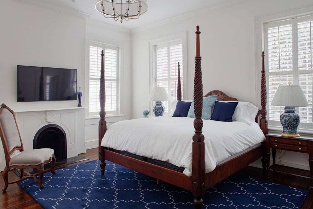 Quarto com cama de dossel, televisão na parede e lareira.