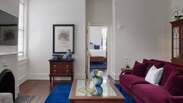 A living room with a blue carpet, a red sofa, a wooden coffee table, and a chandelier.
