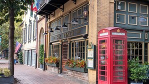 Een traditionele pub met een rode telefooncel en een gevel van baksteen.