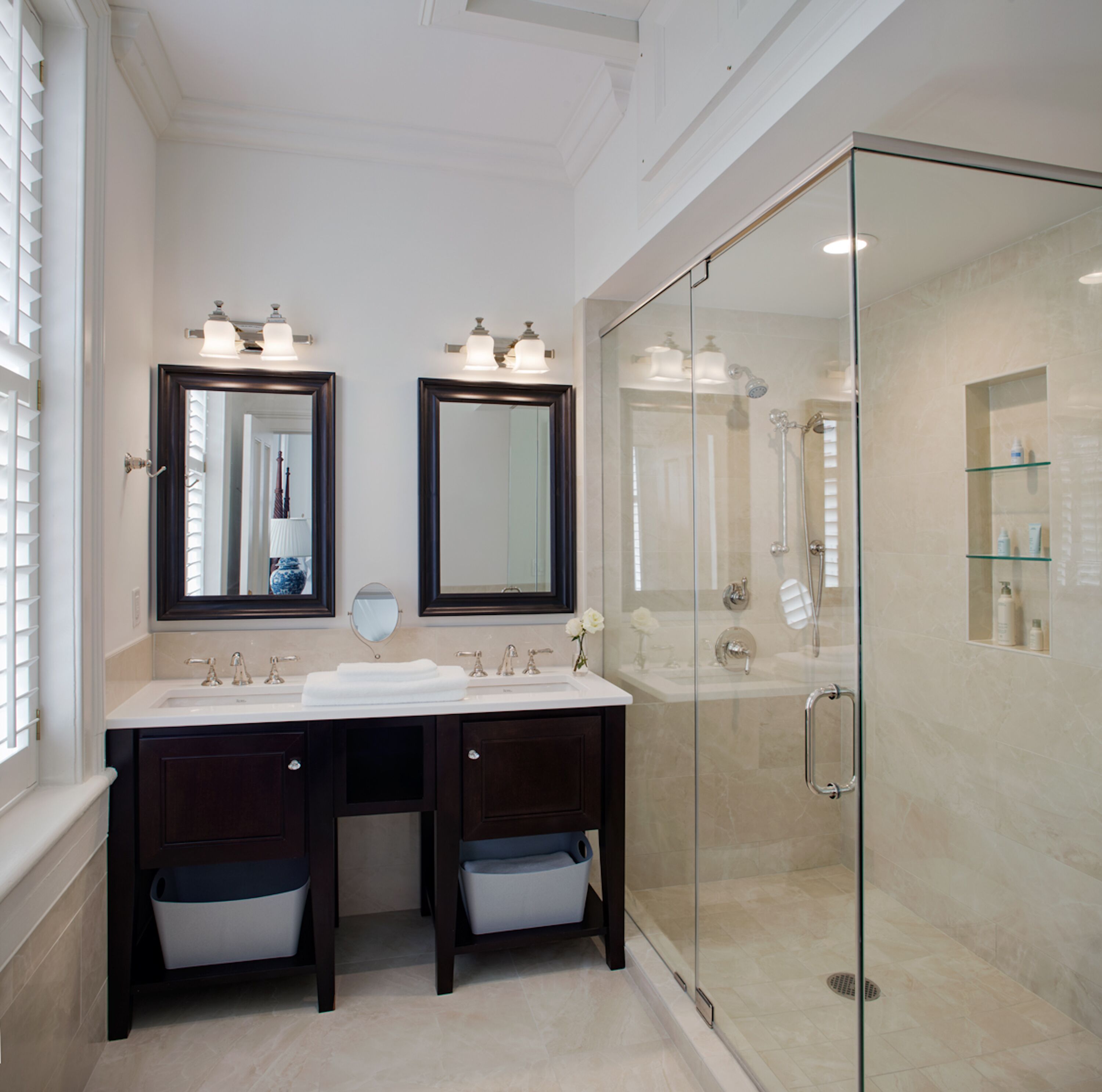A modern bathroom with two sinks, a glass shower enclosure, and a large mirror above the sinks.