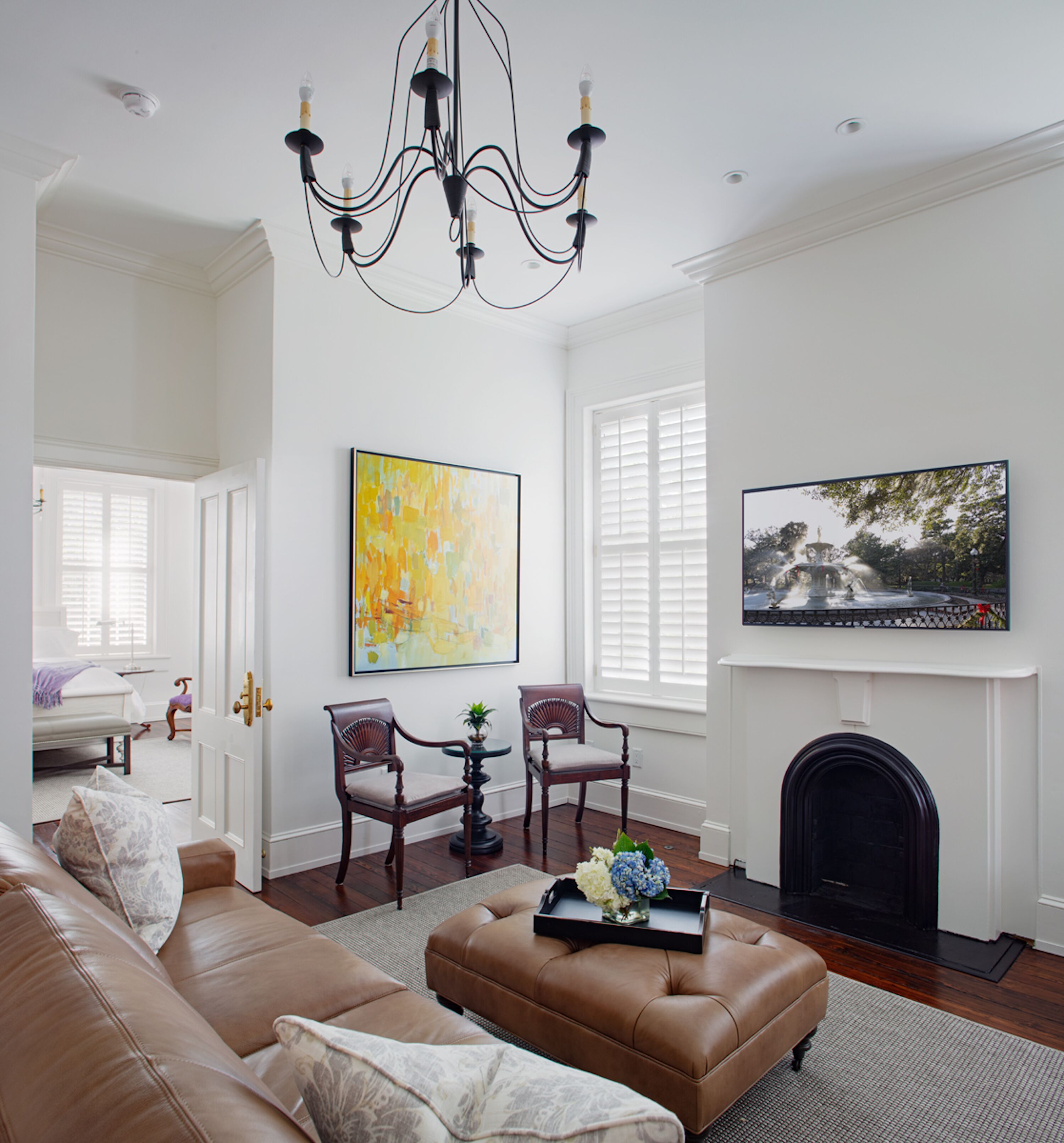 A spacious living room with a fireplace, a large TV, and a chandelier.