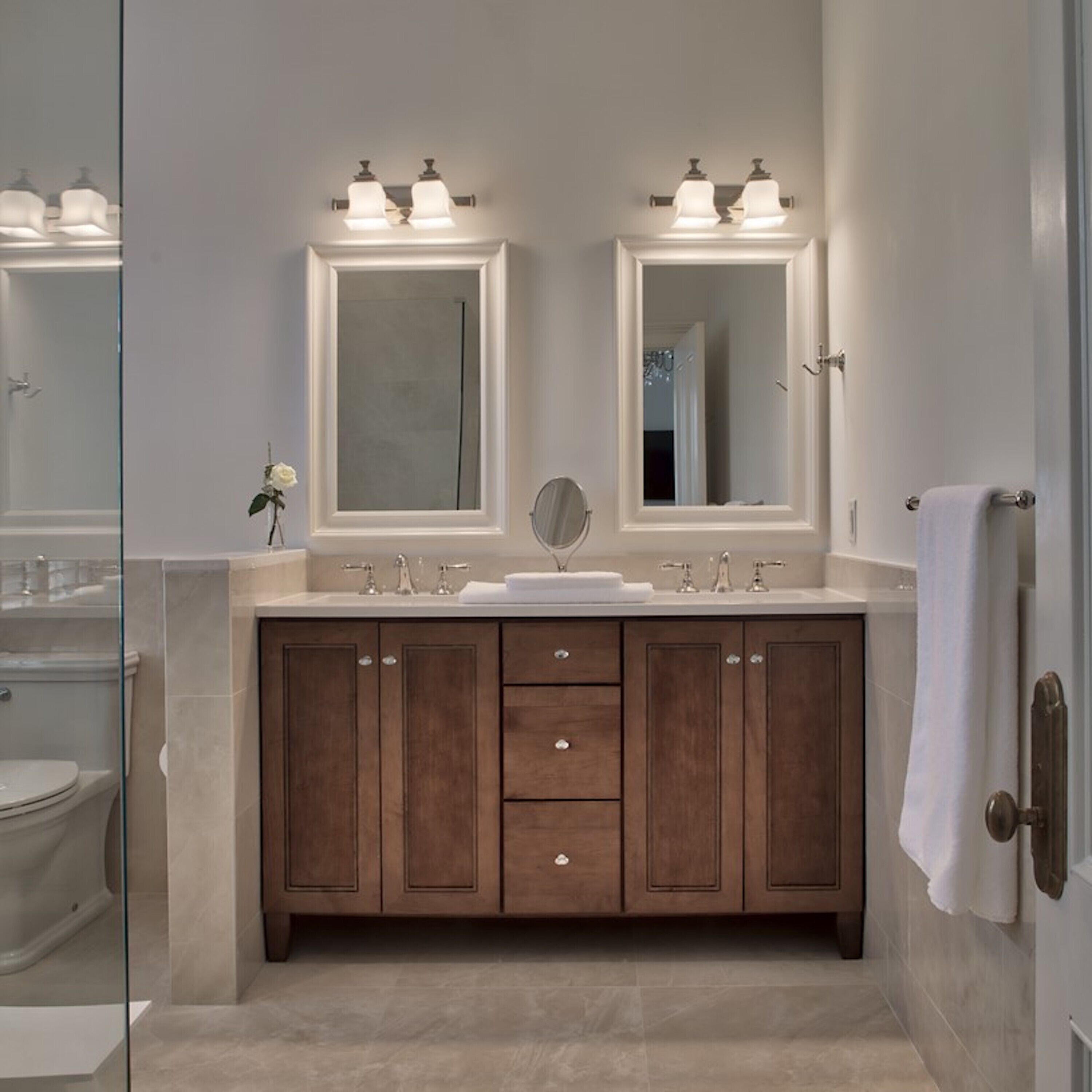 A bathroom with a double vanity, two mirrors, a sink, and a toilet.
