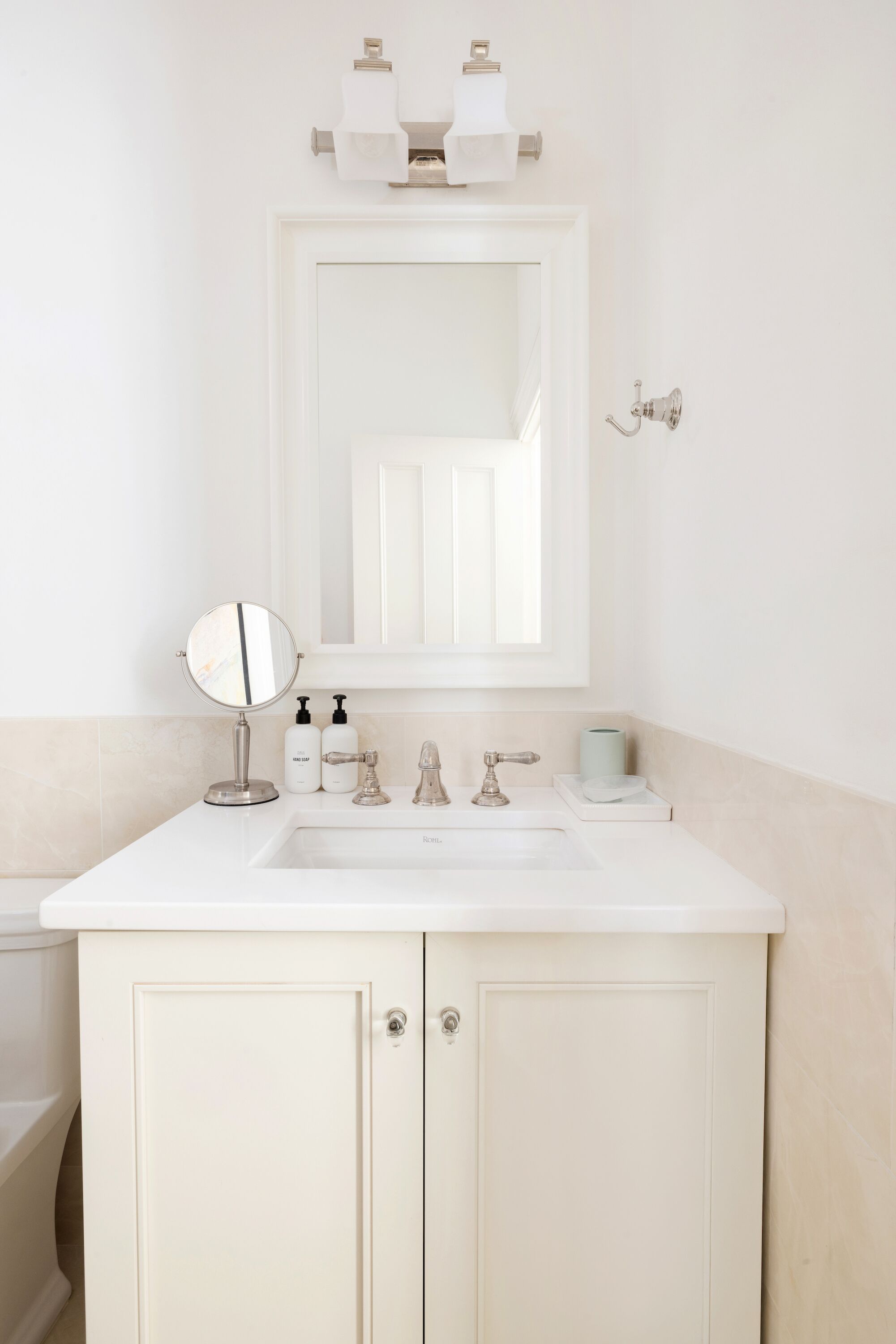 A bathroom with a white sink, a round mirror, and two wall-mounted light fixtures.