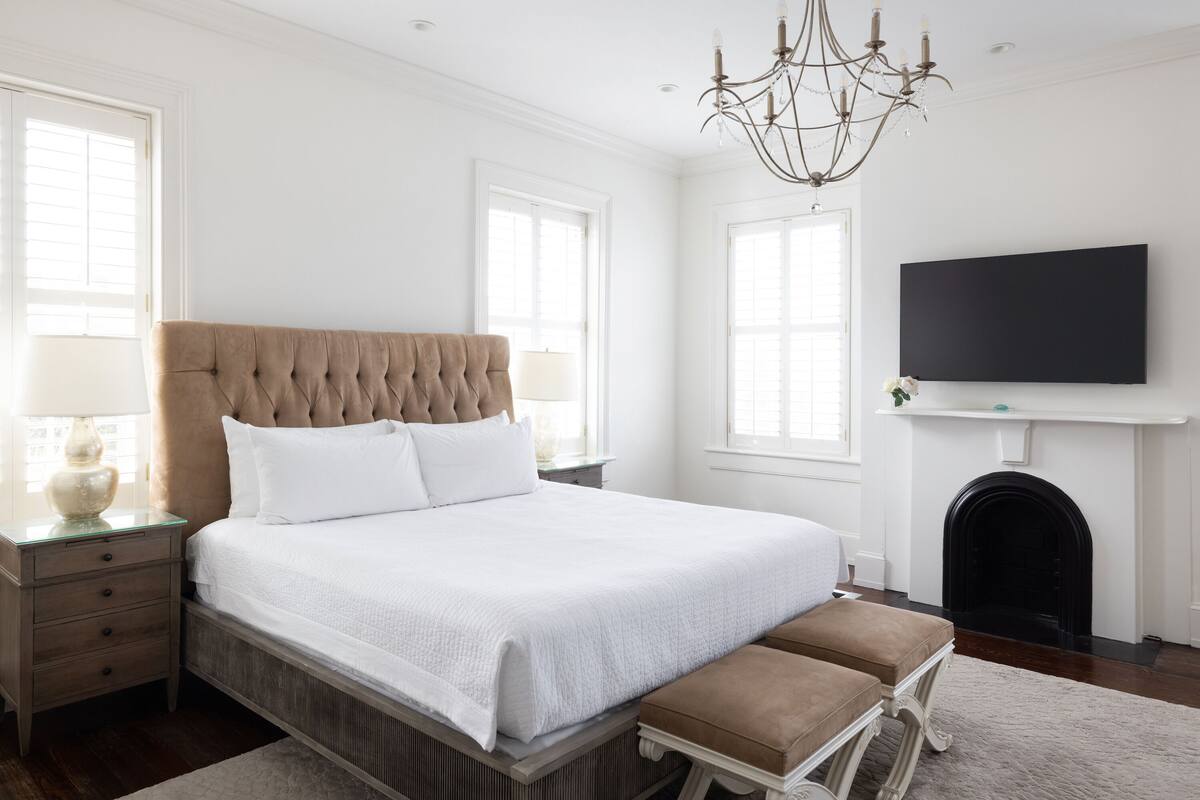 Quarto com uma cama grande, uma televisão sobre a lareira e um candelabro.