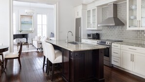 Een moderne keuken met een groot eiland, witte keukenkastjes en een roestvrijstalen afzuigkap.