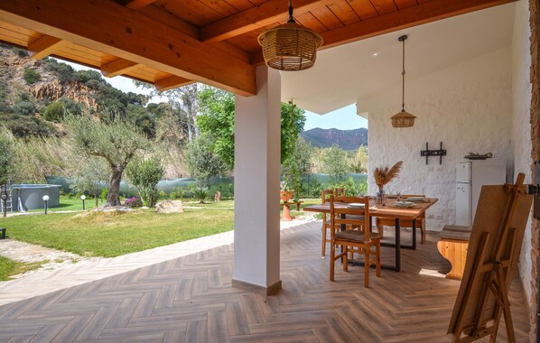 A covered patio with a wooden table and chairs, a herringbone-patterned floor, and a view of a lake and hills. - Cozy home in Solanas, Sinnai with WiFi (Solanas, Sinnai)