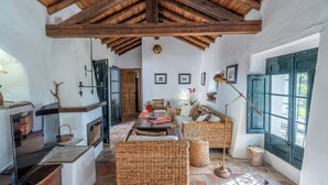 Un intérieur rustique avec une cheminée, des meubles en osier et un plafond en bois.