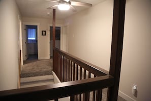 Staircase leads to an upper floor with a carpeted landing and ceiling fan.