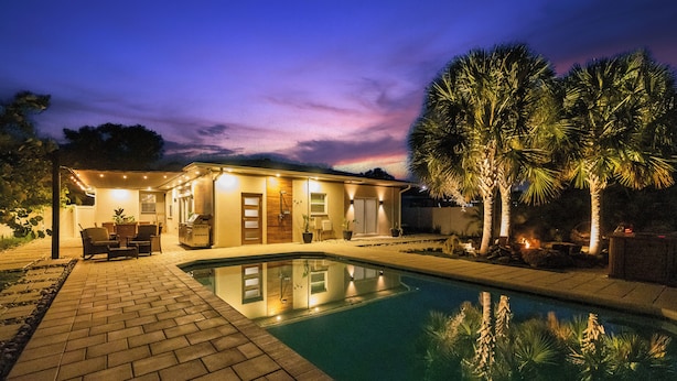 A house with a swimming pool, outdoor seating, and a patio area.
