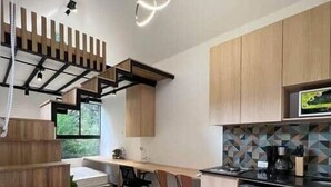 A modern kitchen with wooden cabinets, a built-in stove, and a dining area with a table and chairs. - Frontera by Roots Rentals (Medellín)