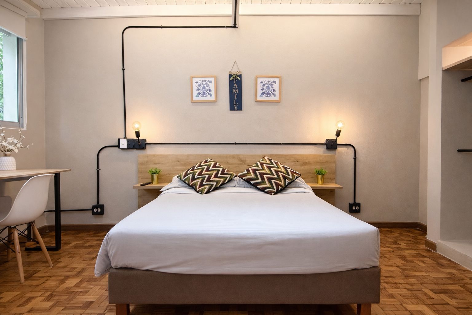 Un dormitorio con cama, dos mesitas de noche, un escritorio y una ventana.