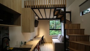 A modern kitchen with a wooden countertop, a built-in microwave, and a dining area with chairs. - Frontera by Roots Rentals (Medellín)