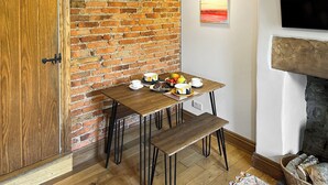 Een gezellige kamer met een bakstenen muur, een houten deur, een tafel met een fruitschaal, een kopje en een bord koekjes.