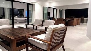 A modern living room with a wooden coffee table, white sofas, and a large glass wall. - Ripple Negril, The ultimate escape. Unpack, Relax, Enjoy, Ripple Negril, The ultimate escape (West End)