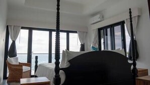 A four-poster bed in a room with large windows, a view of the sea, and a ceiling fan. - Ripple Negril, The ultimate escape. Unpack, Relax, Enjoy, Ripple Negril, The ultimate escape (West End)