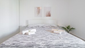 A modern hotel room with a large bed, neatly arranged towels, and two framed leaf artworks on the wall.