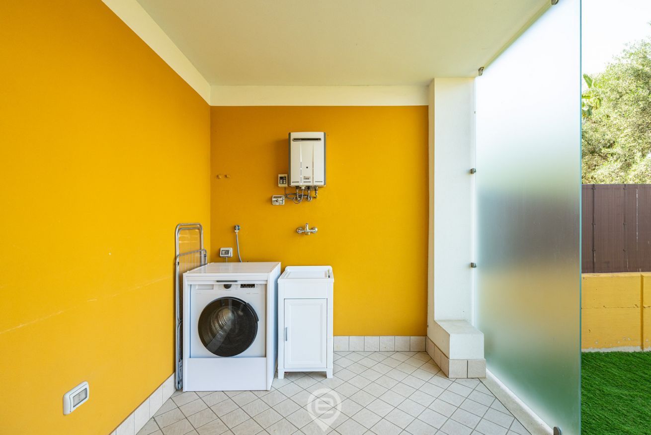 A compact laundry room with a washing machine, dryer, and a water heater on the wall.