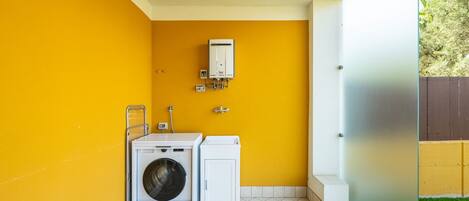 A compact laundry room with a washing machine, dryer, and a water heater on the wall.