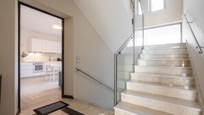 A modern interior with a staircase, a kitchen area, and a glass railing.