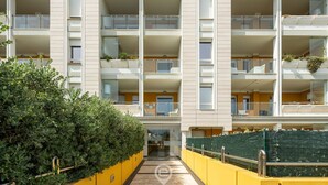 A multi-story residential building with balconies, a central entrance, and a yellow and white color scheme.