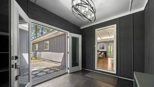 A modern entryway with a sliding glass door leading to a covered outdoor area. - Picturesque Lakeside Luxury: Perfect Lush Getaway (Hampton)