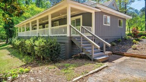 A two-story house with a covered porch and a staircase leading to the upper floor. - Picturesque Lakeside Luxury: Perfect Lush Getaway (Hampton)