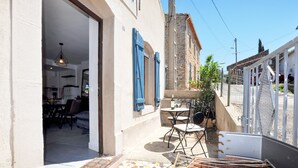 Une rue étroite bordée d’un immeuble qui possède un petit espace extérieur aménagé avec une table et des chaises.
