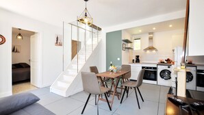 Un appartement moderne comprenant un coin repas, une cuisine et un escalier.