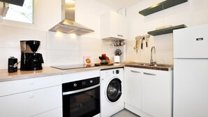 Une cuisine moderne avec des meubles blancs, une machine à café, un lave-linge et un évier.