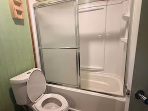 Un baño con inodoro, cabina de ducha y puerta de cristal.