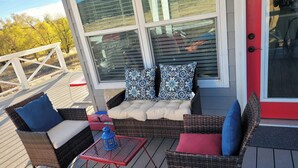 Un espace extérieur aménagé, abrité et doté de mobilier en osier, de coussins et d’une petite table.