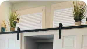 Un dressing accessible sans porte, une étagère avec des plantes et un miroir.